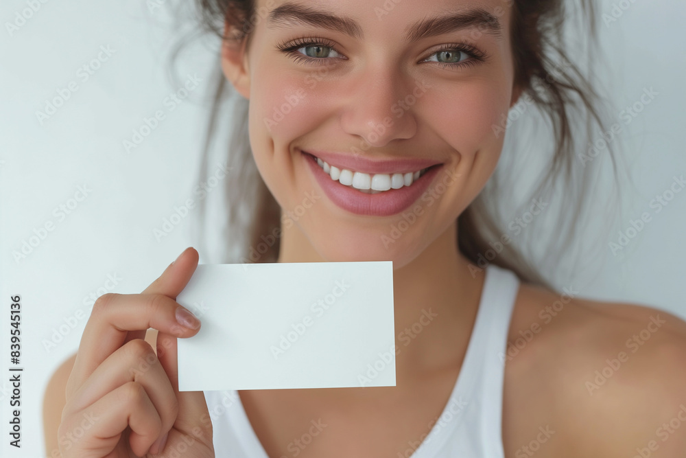 Cute girl holding white card at front of her lips with copy space on a white background