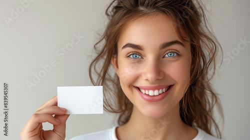 Cute girl holding white card at front of her lips with copy space on a white background