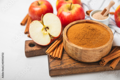 Apples with cinnamon on a textured wooden background. Fragrant red spiced apples with cinnamon sticks and star anise. Apple slices with spicy spices. Place for text. Copy space. Harvesting. Fruits.