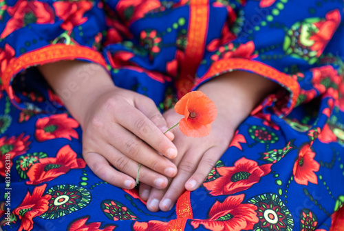 Young Girl's Hands Holding a Red Poppy Flower Against a Colorful Yuruk Dress. Heal the world. Peace, concept. photo