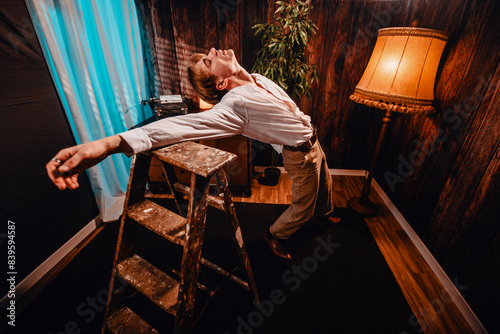 Bold Vogue: Blonde Adonis in Crisp White Shirt Strikes an Artistic Pose Against an Antique Ladder, Captivating with High-Fashion Flair in a Nostalgic Retro Room photo