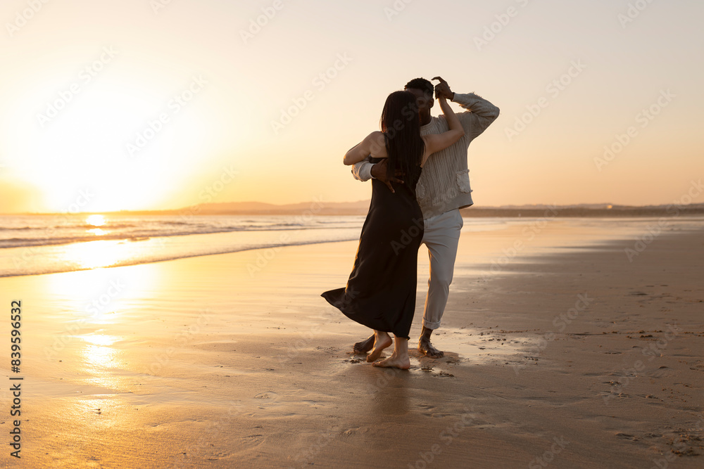 Fototapeta premium A couple is dancing on the beach at sunset