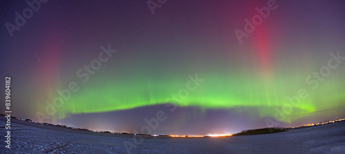 Polar lights over a snow field. Panoramic shot.