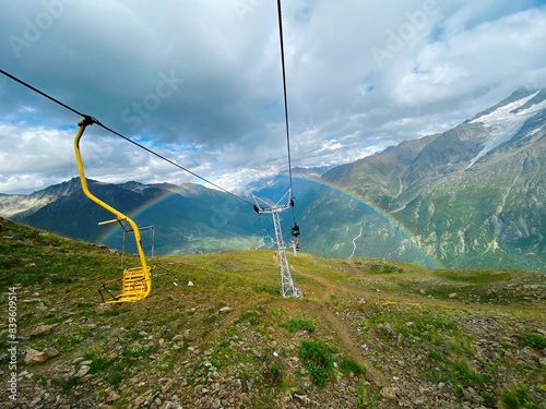 Rainbow in the mountains. Old cable car in the mountains. Full rainbow and yellow mechanism for climbing up the mountains, Elbrus region