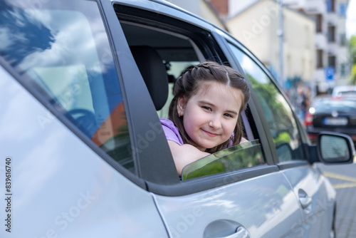 The girl sits in the car and looks out of the car window