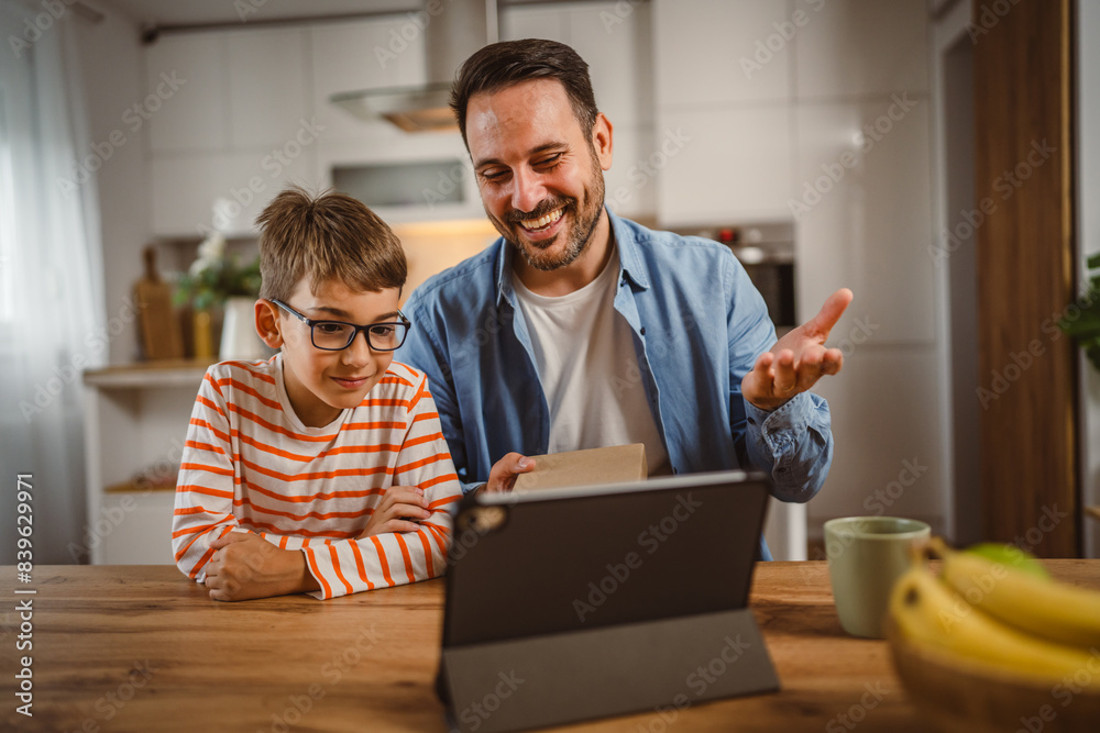 Father and son open birthday present home with tablet on the table Father and son open birthday present home with tablet on the table