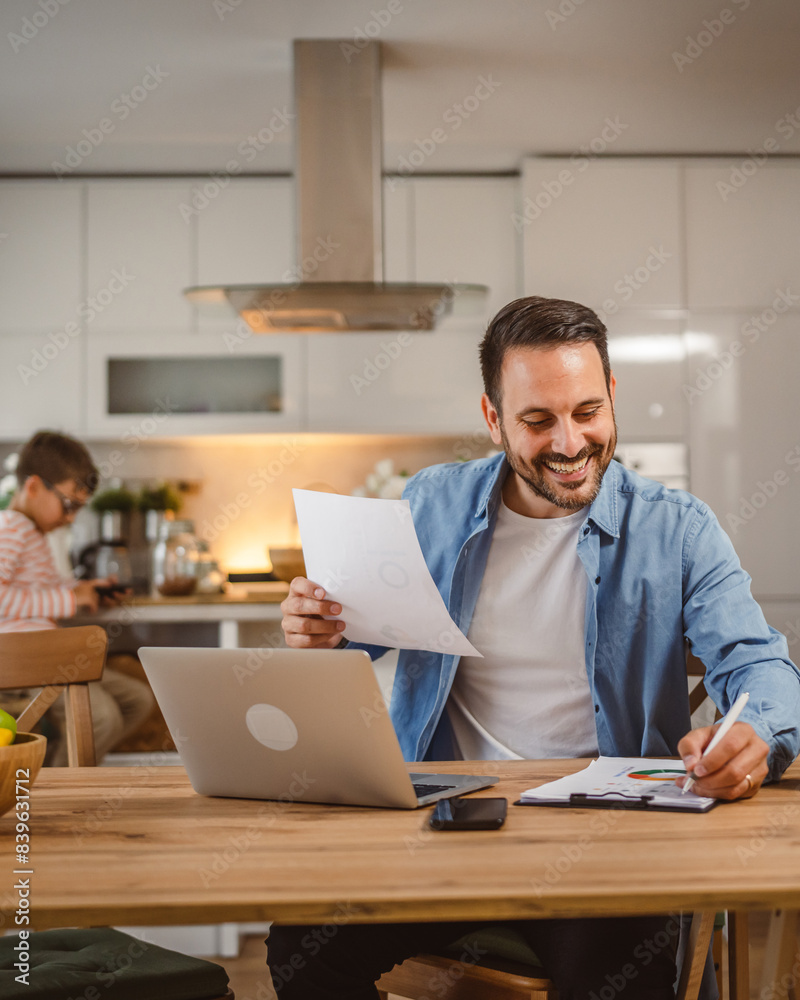 Father write on document and use laptop with son at background Father write on document and use laptop with son at background
