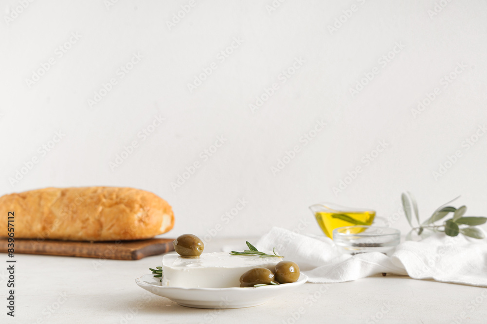 Plate with tasty feta cheese, olives and rosemary on white background Plate with tasty feta cheese, olives and rosemary on white background