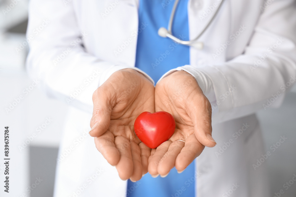 Mature female doctor with heart in clinic, closeup Mature female doctor with heart in clinic, closeup
