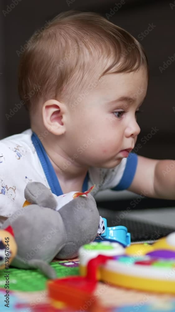Sweet little kid lying on the floor crawling closer to his toys. Lovely child choosing car among other toys. Close up. Vertical video Sweet little kid lying on the floor crawling closer to his toys. Lovely child choosing car among other toys. Close up. Vertical video