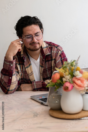 Young man with headache with his laptop in the living room making pain gesture