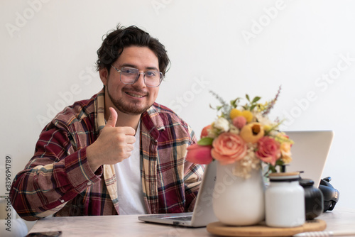 Young man with glasses from his laptop making gesture and wellness vibes concept in the living room