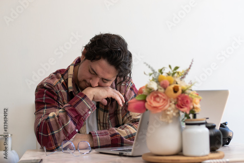 Young man with headache with his laptop in the living room making pain gesture