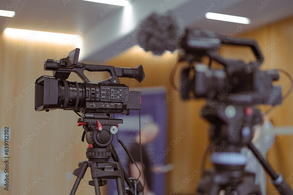 Two broadcast cameras ready on a tripod for a conference or live event or stream. Popularity of live stream is rising, so is equipment