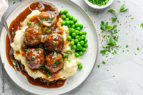 English meatballs with mashed potatoes peas and thick onion gravy on white plate classic British meal