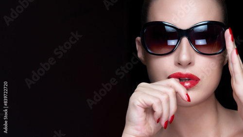 Elegant woman with sunglasses and red lips. High fashion portrait isolated on dark background