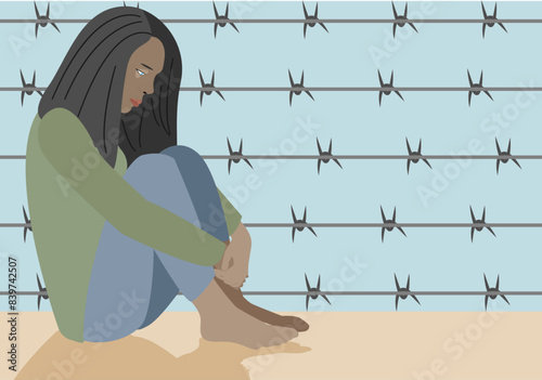 Persona inmigrante sentada deprimida tras la valla de una frontera. photo