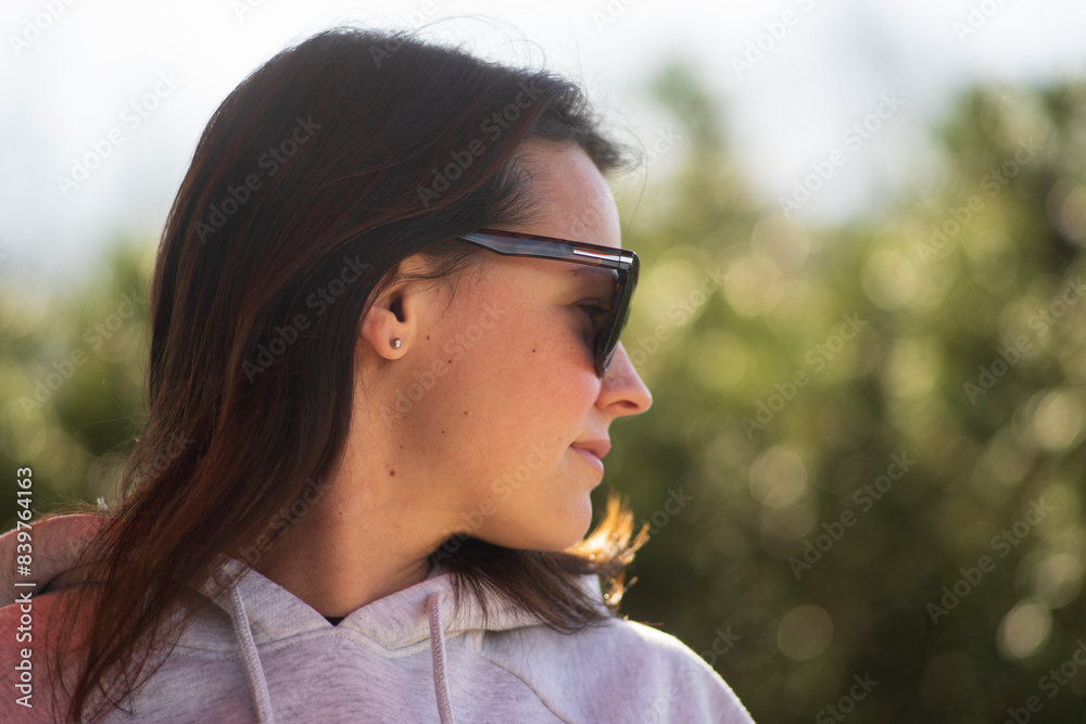 A YOUNG beautiful dark-haired girl in a hoodie and sunglasses looks away in the backyard of her house. Interesting life concept A YOUNG beautiful dark-haired girl in a hoodie and sunglasses looks away in the backyard of her house. Interesting life concept