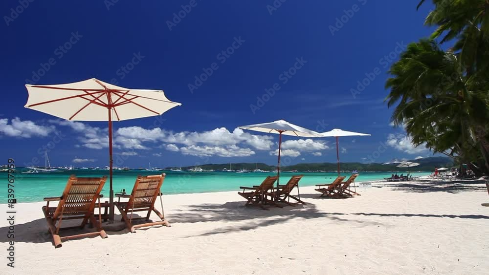 Sun umbrellas and beach chairs on tropical beach with palm trees. Summer vacation. Boracay