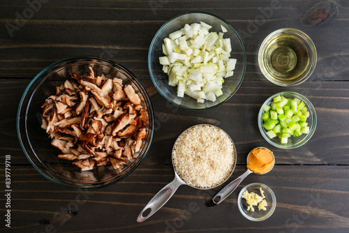 Mushroom Risotto Ingredients on a Wooden Table: Uncooked arborio rice with raw shiitake mushrooms, diced onion and celery, white wine, and more photo