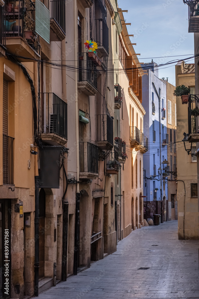 Fototapeta premium Walking through a Narrow Street with Charming Historic Buildings and Balconies under a Clear Sky