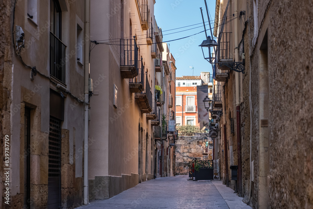 Fototapeta premium Walking through a Narrow Street with Charming Historic Buildings and Balconies under a Clear Sky