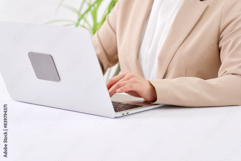 Fototapeta premium オフィスでパソコンを使ってデスクワークをする若いビジネスウーマン 顔無し