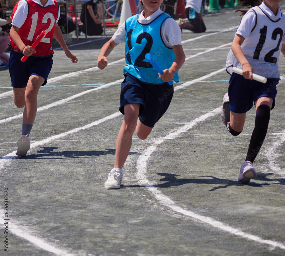 小学校の運動会の学生たちのリレーの走る姿