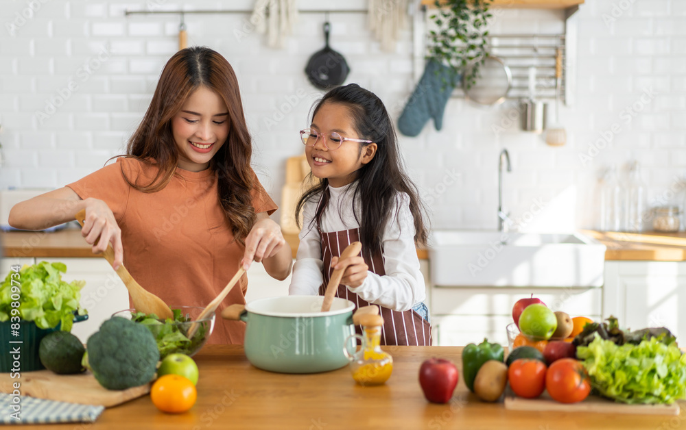 Portrait of enjoy happy love asian family mother with little asian girl daughter child help cooking food healthy eat with fresh vegetable testing smell soup in a pot with spoon.helping mom in kitchen Portrait of enjoy happy love asian family mother with little asian girl daughter child help cooking food healthy eat with fresh vegetable testing smell soup in a pot with spoon.helping mom in kitchen
