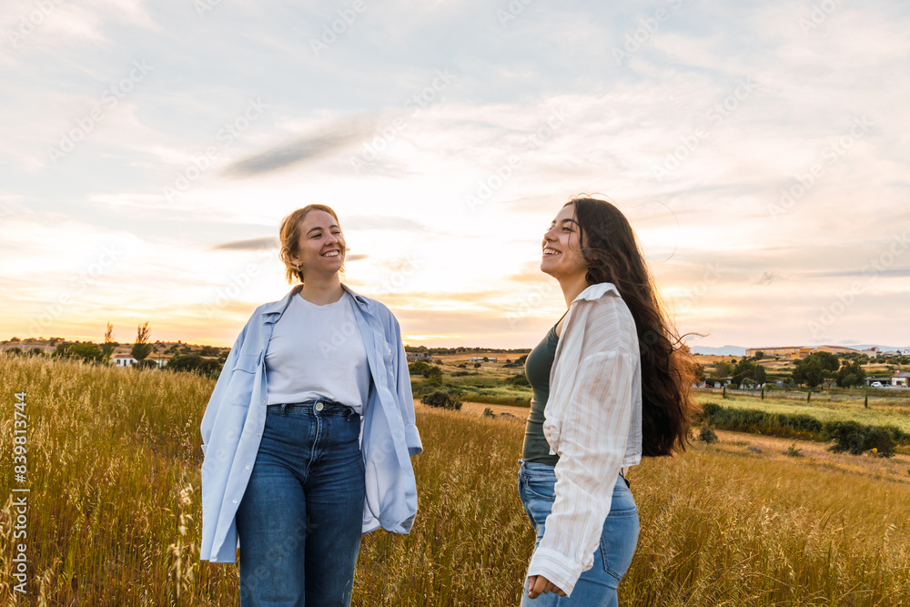 blonde an brunette women smiling in a field at sunset blonde an brunette women smiling in a field at sunset