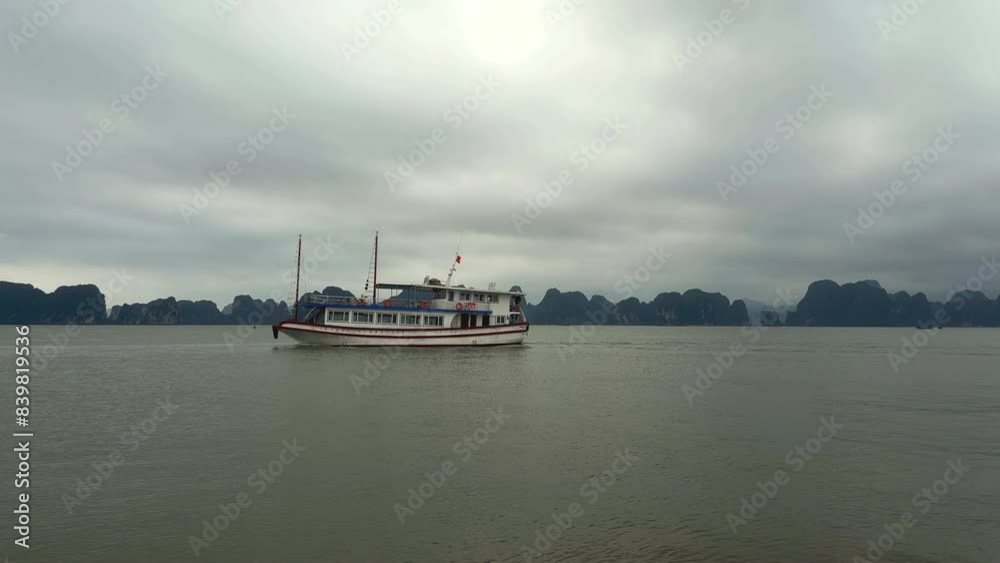 View of ferry sailing with rocky karst mountains in the background. Limestone karst mountains in the Ha Long Bay archipelago. Ha Long Bay, Vietnam. View of ferry sailing with rocky karst mountains in the background. Limestone karst mountains in the Ha Long Bay archipelago. Ha Long Bay, Vietnam.