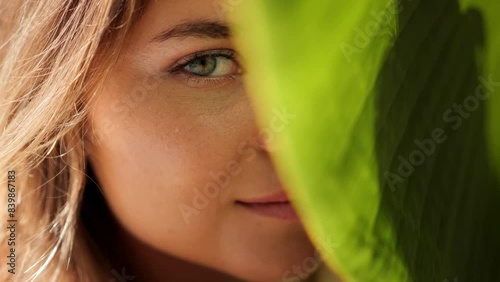  Face of young woman with clean skin with natural makeup among banana leaves