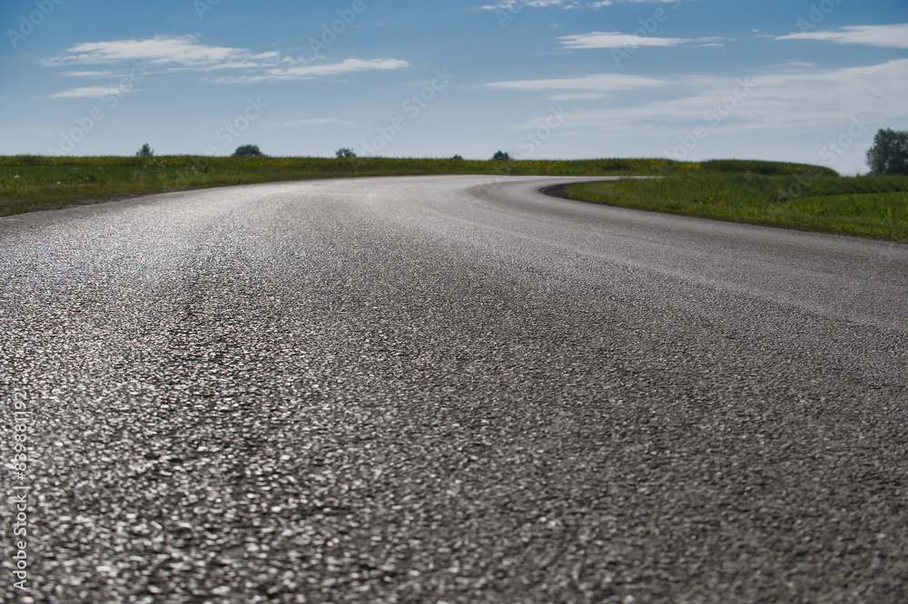 Sunlit winding road through a scenic countryside with blue sky Sunlit winding road through a scenic countryside with blue sky
