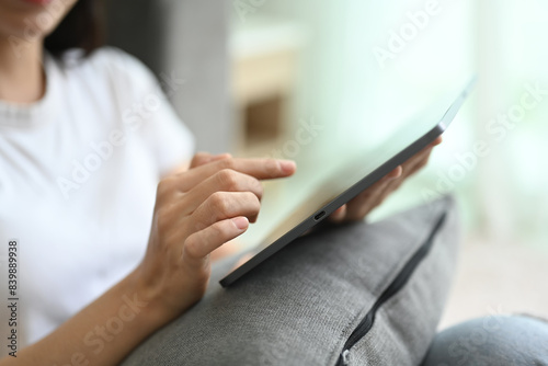 Close up young woman in casual clothes surfing internet on digital tablet at home