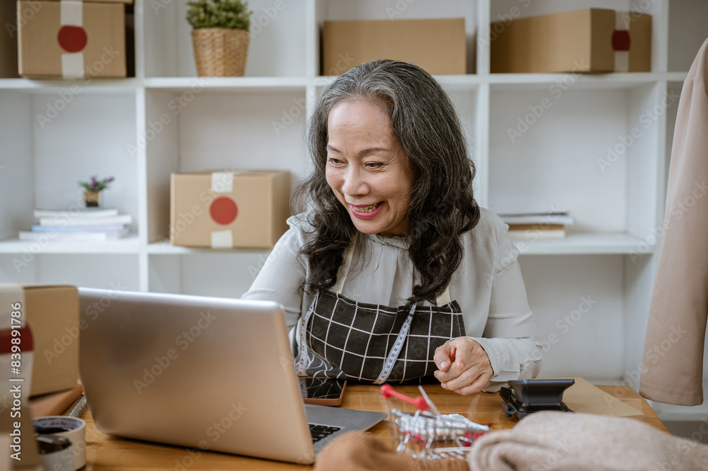 A mature female online seller is checking online orders on her shopping website on her computer. A mature female online seller is checking online orders on her shopping website on her computer.