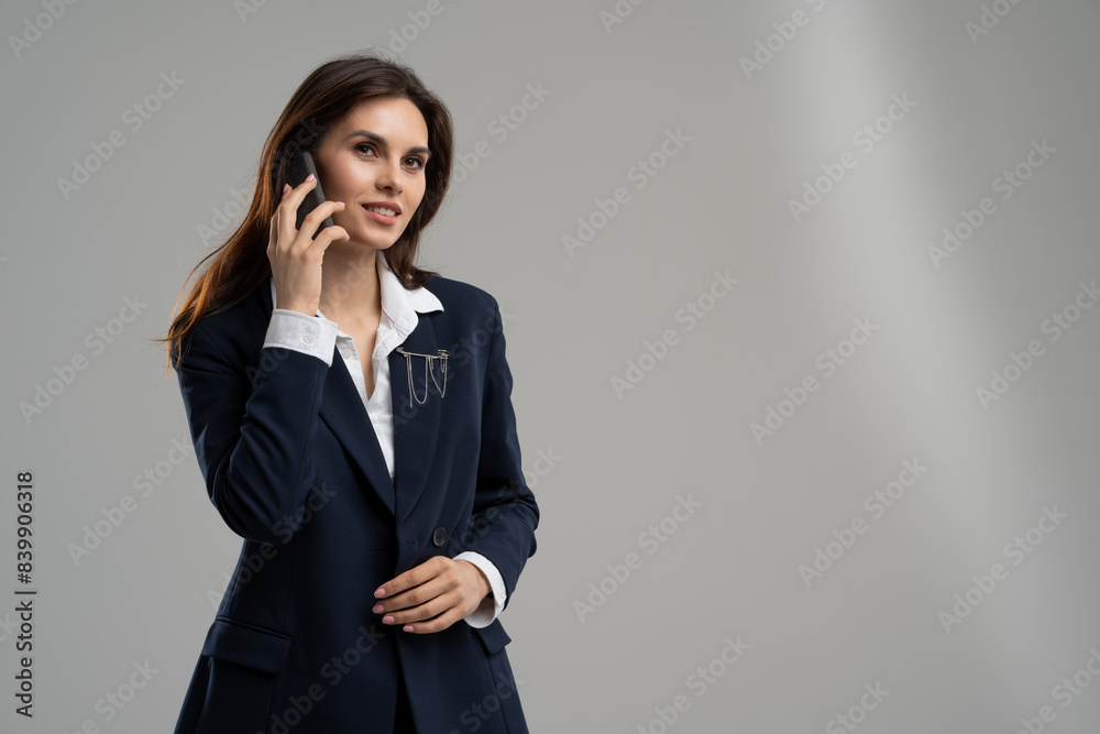 A woman in a business suit is talking on a cell phone A woman in a business suit is talking on a cell phone