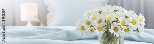 A white vase with yellow flowers sits on a nightstand next to a lamp. The scene is peaceful and calming  with the flowers adding a touch of natural beauty to the room