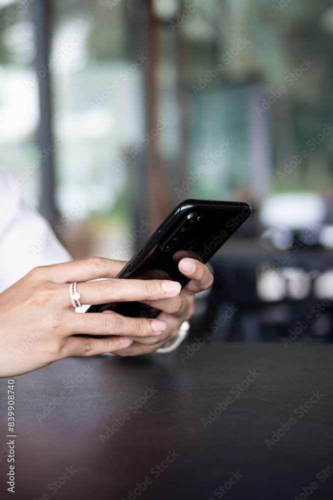 Close up of woman hand using modern smart phone while working in office with computer. and typing a text message on his cell phone. Close up of woman hand using modern smart phone while working in office with computer. and typing a text message on his cell phone.