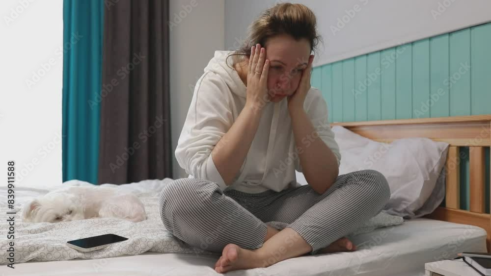 Young Woman Feeling Overwhelmed Sitting on Her Bed With Smartphone in Morning Light
