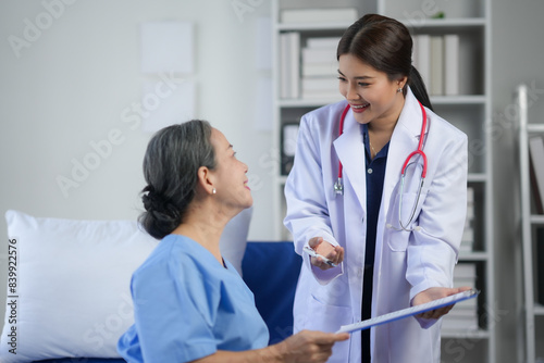 Friendly doctor consulting with a senior patient in a hospital room, discussing treatment and care options with a smile.