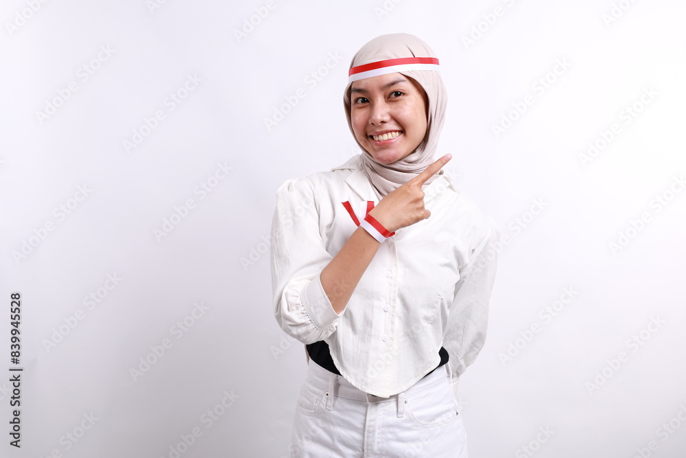 Happy young Asian muslim woman standing while pointing fingers aside at copy space isolated on white background. Indonesian independence day on 17 august concept Happy young Asian muslim woman standing while pointing fingers aside at copy space isolated on white background. Indonesian independence day on 17 august concept
