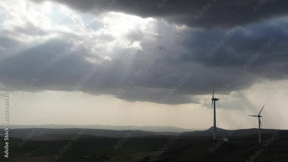 Two windy power systems against the backdrop of the sun's rays between the clouds captured by a drone Two windy power systems against the backdrop of the sun's rays between the clouds captured by a drone