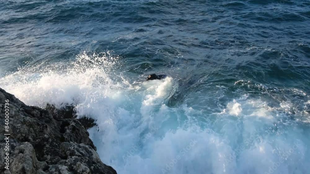 Ocean waves rocks slow motion. Huge foaming waves roll on the stone shore. Dark blue turquoise sea water. The concept of the elements, windy weather, tropical climate. Fascinating movement of water. Ocean waves rocks slow motion. Huge foaming waves roll on the stone shore. Dark blue turquoise sea water. The concept of the elements, windy weather, tropical climate. Fascinating movement of water.
