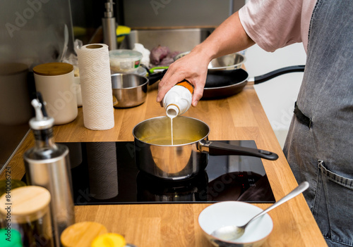 Chef at the kitchen preparing green curry with herbs and rice