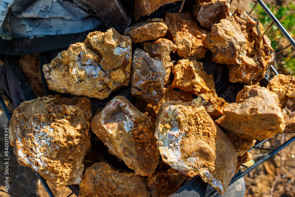 Beautiful stones collected in a basket for collection, rockhounding. The flints are covered with bright sintered chalcedony Beautiful stones collected in a basket for collection, rockhounding. The flints are covered with bright sintered chalcedony