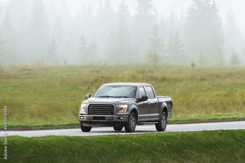 Black pickup truck cruising on a road beside beautiful nature Black pickup truck cruising on a road beside beautiful nature