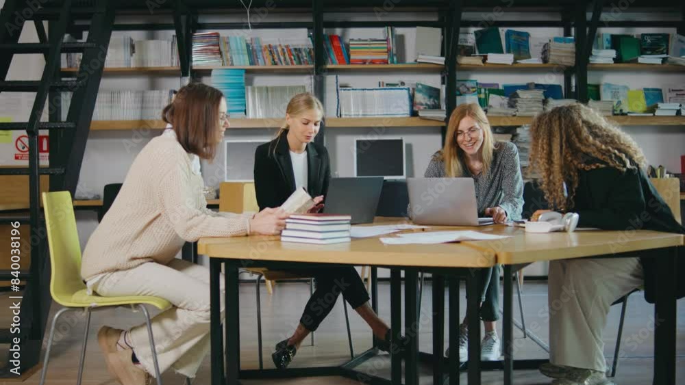 a group of young beautiful businesswomen sit at a round table and work with important documents, books and laptops. Girls work in the library and do business a group of young beautiful businesswomen sit at a round table and work with important documents, books and laptops. Girls work in the library and do business