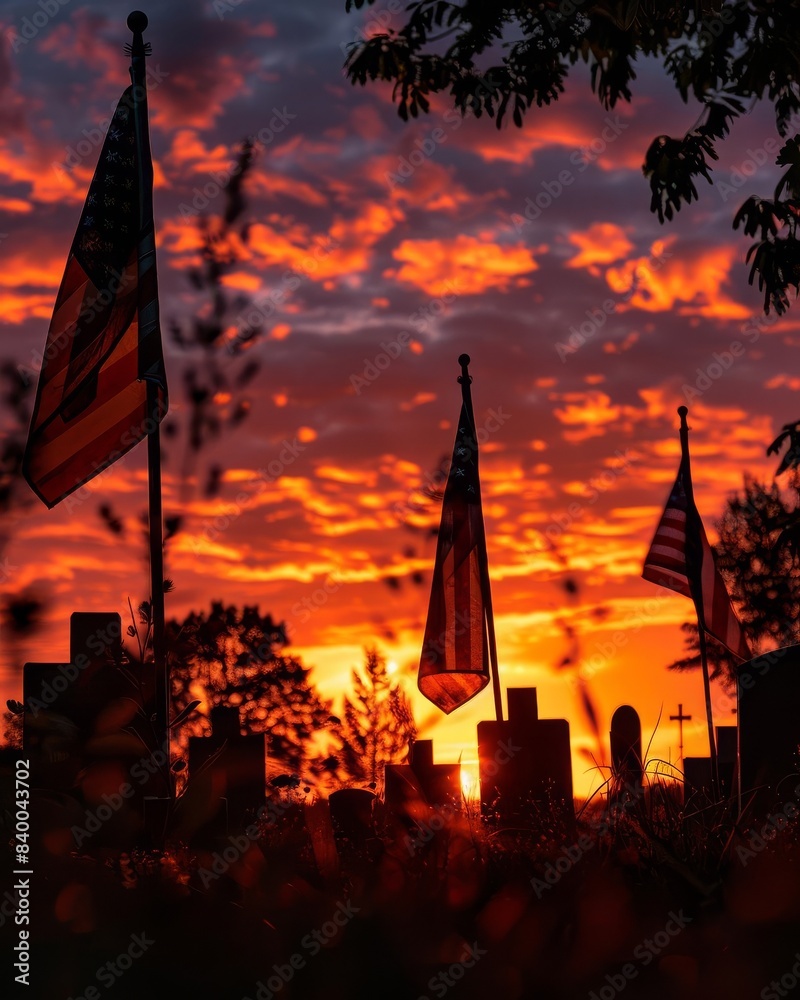 Naklejka premium Dramatic sunset with American flags silhouetted against a vibrant sky, creating a striking scene of patriotism and natural beauty.