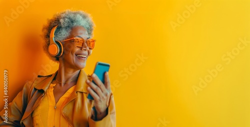 Senior model, stylish in yellow, listens to music with a clean background for your message.
