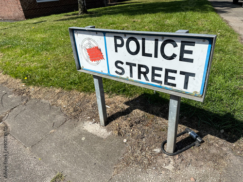 Post mounted Police Street name sign or street name plate on pavement or sidewalk on city road in the United Kingdom.